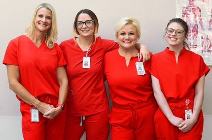 All four of the Clinton Regional Hospital Cardiac Rehab team wearing red scrubs and smiling as they stand together.