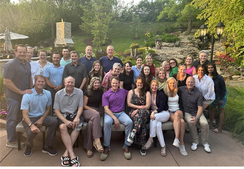 A group of coworkers stand and sit for a group picture.