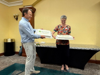 Pritikin ICR President, Terry Rogers stands holding up a white cake highlighting 200 openings. Next to him is our Marketing Director holding a second white cake.