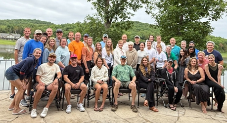 A group photo of the Pritikin ICR team posing on an outdoor patio after a day at the lake. 