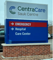 The sign outside of CentraCare Sauk Centre indicating that the Emergency room and Hospital's Care Center are in the same direcion. 