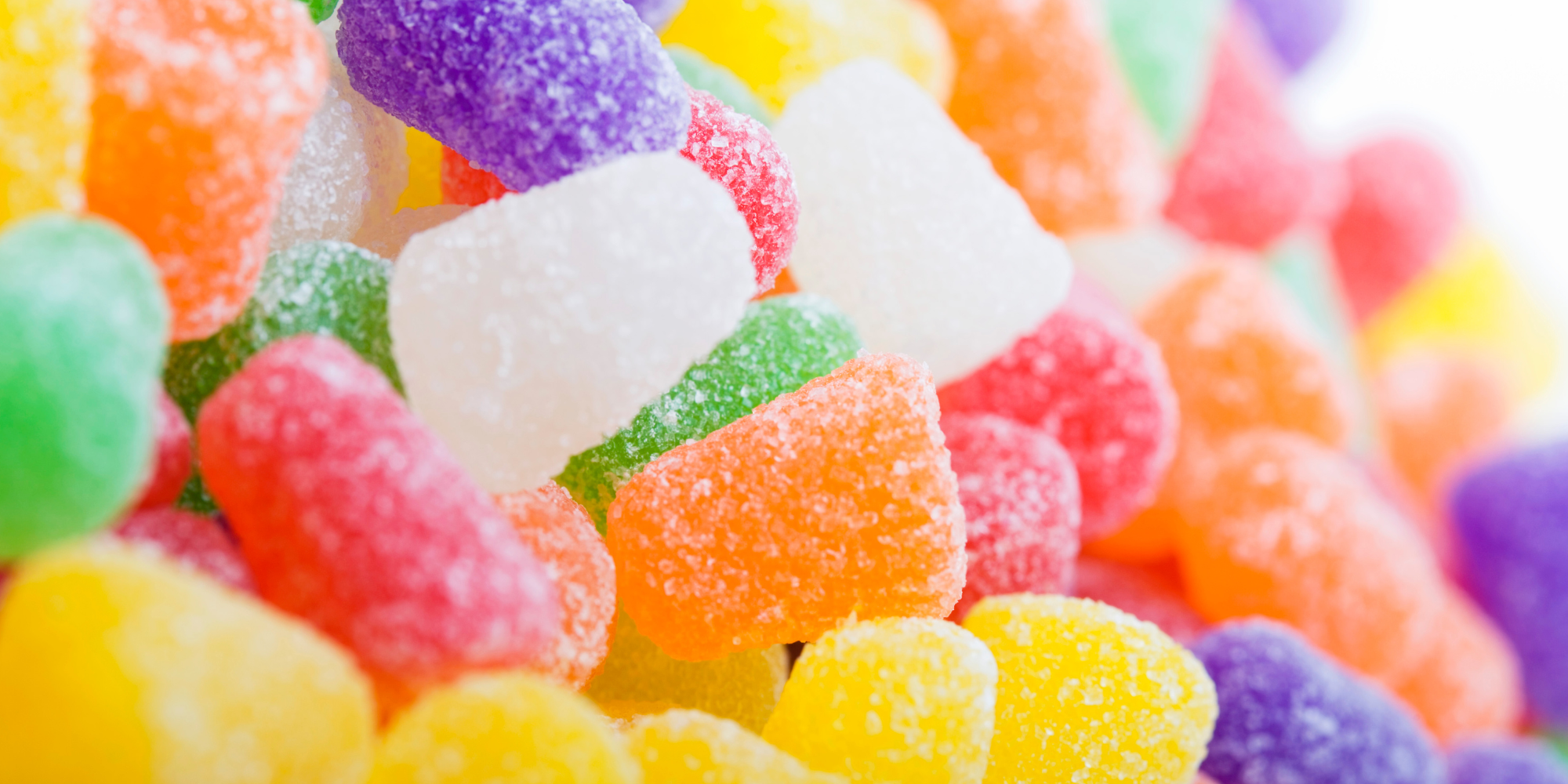 Colorful candy gumdrops dusted in sugar fading in focus towards the right of the image