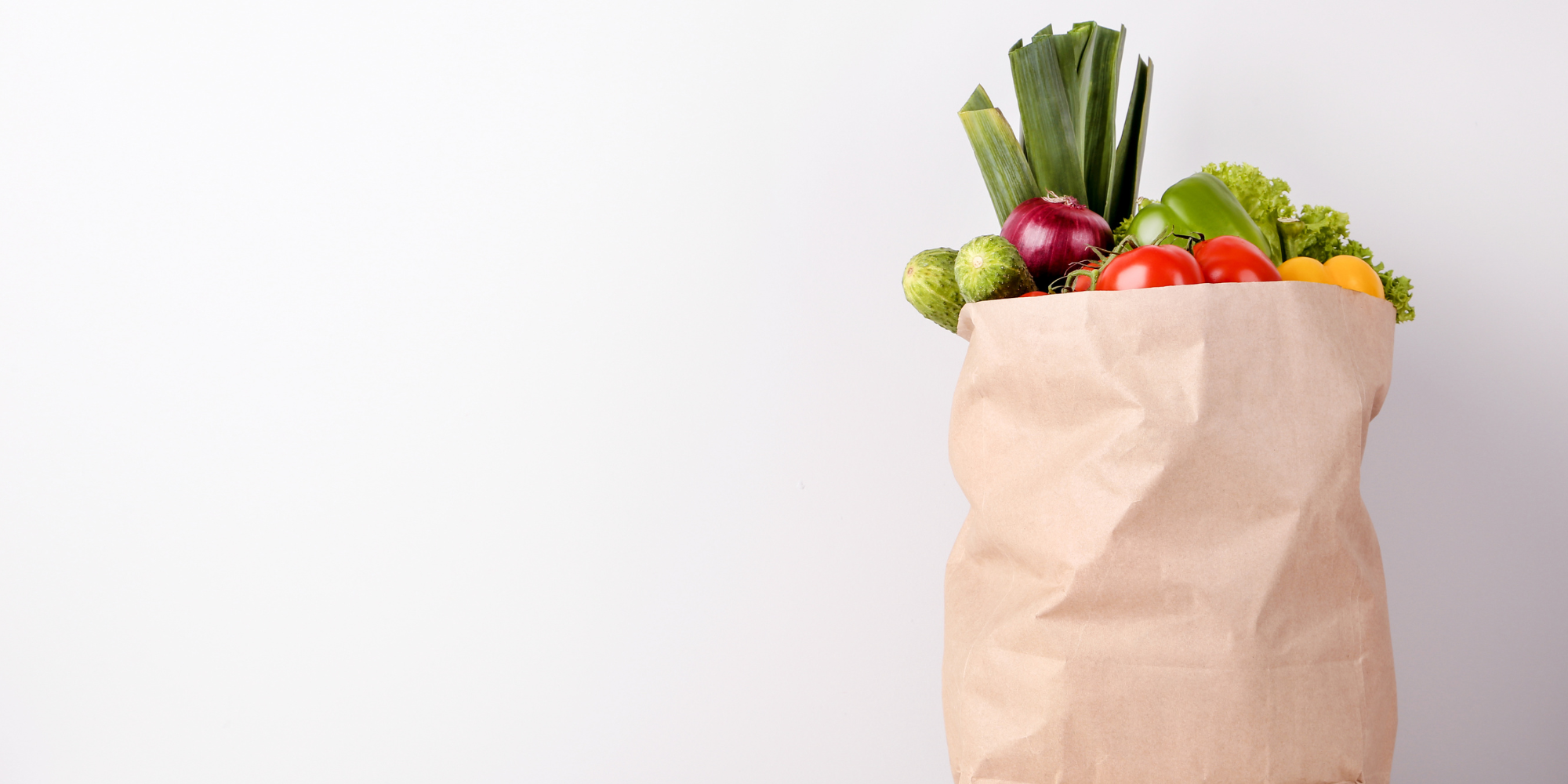 Brown paper grocery bag full of colorful vegetables