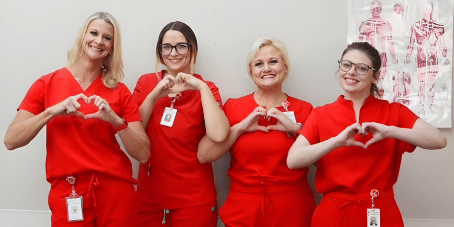 Clinton Regional Hospital Intensive Cardiac Rehab team of four women wearing red scrubs making a heart sign with their hands as they smile at the camera