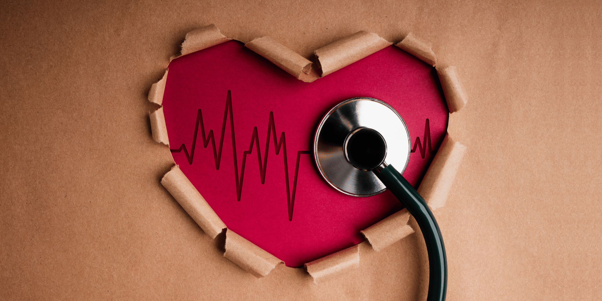 brown wrapping paper cut out in the shape of a heart to reveal a red heart underneath. A stethoscope is on the heart capturing the Electrocardiogram over the heart. 