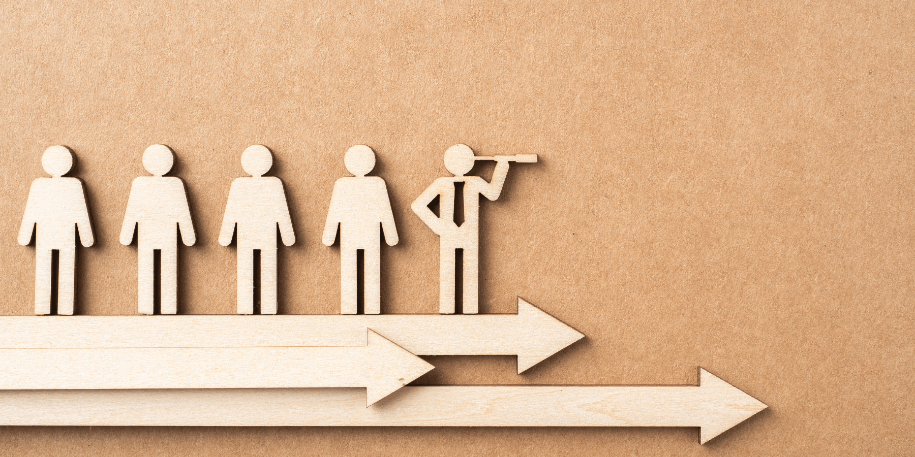 wooden cut out image of people looking towards the right/future the person in the center is holding a telescope looking ahead. Below the people are arrows pointing to the right